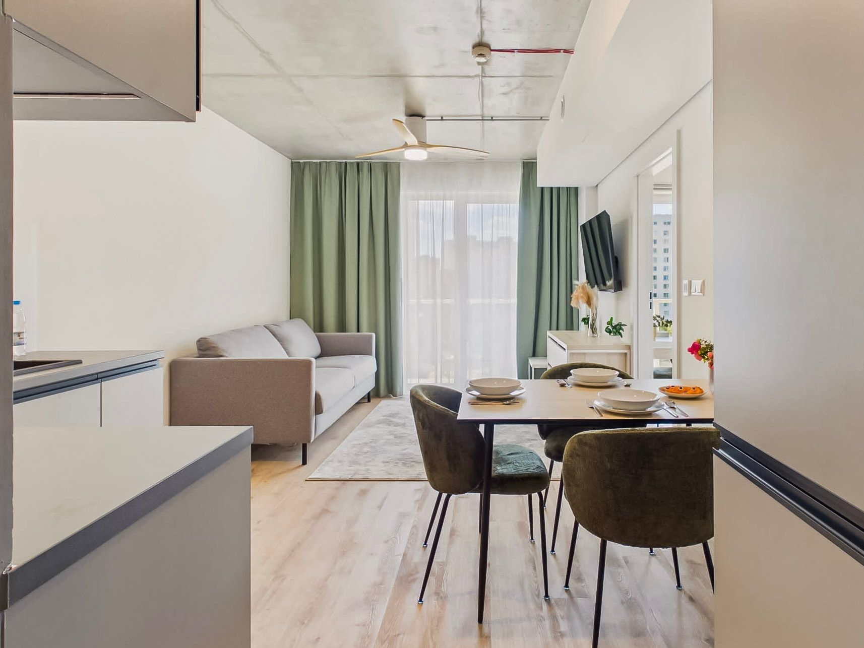 Nowoczesny apartament z salonem i jadalnią, sofą, stołem, krzesłami i zielonymi zasłonami