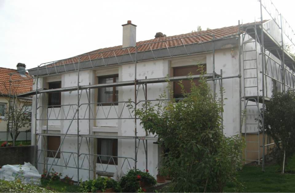 Die Hausfassade befindet sich im Bau, mit Gerüst und weissen Dämmplatten.