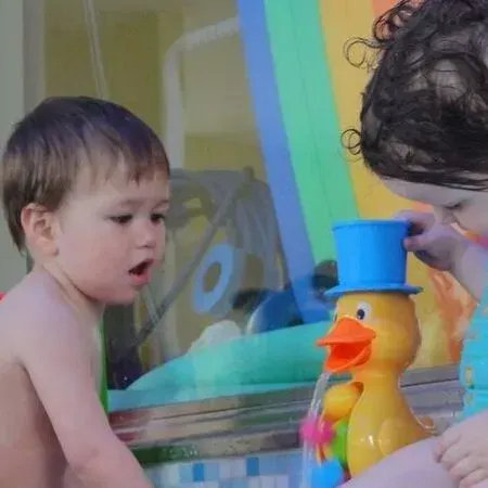 Kind beobachtet drinnen eine bunte Spielzeugente mit blauem Hut