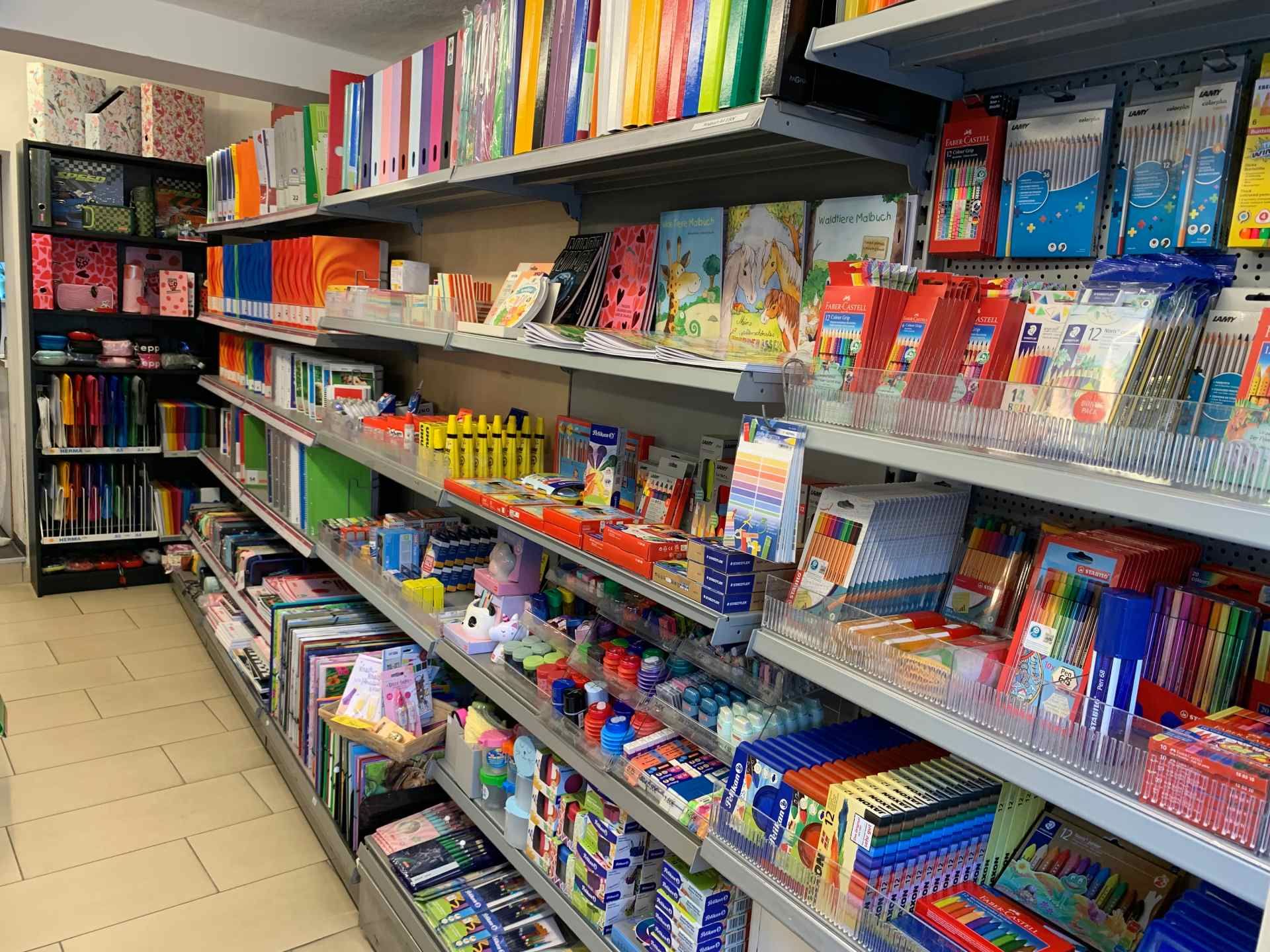 Ein Ladengang mit Regalen voller bunter Schreibwaren, Notizbücher und Schulbedarf.