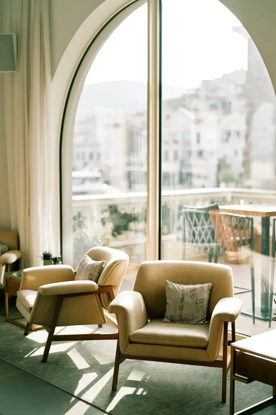 Dos sillones de color beige, de estilo moderno de mediados de siglo, se encuentran sobre una alfombra.