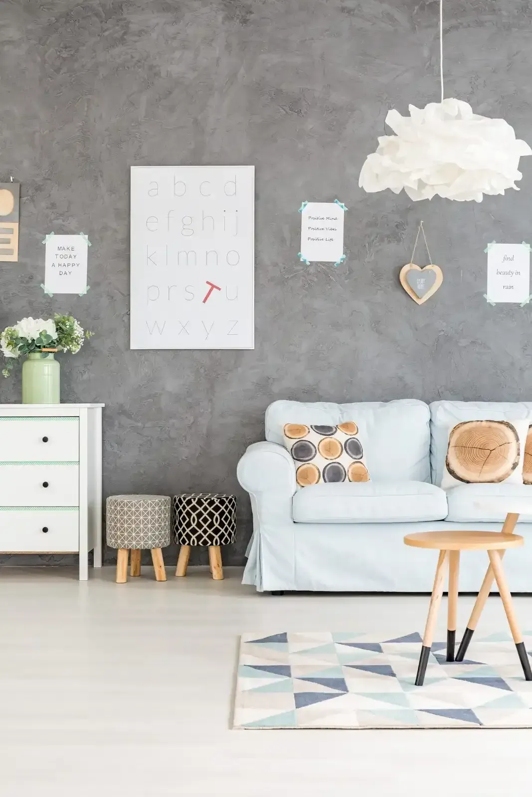 Un sofá azul claro se encuentra frente a una pared gris texturizada decorada con cuadros enmarcados.