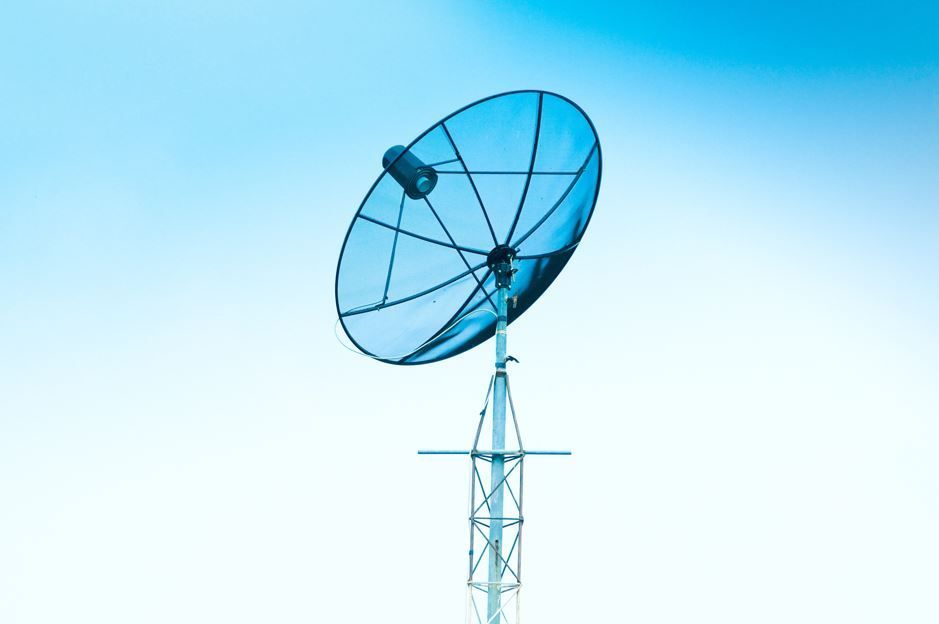 Antena parabólica sobre una torre de metal contra un cielo azul.