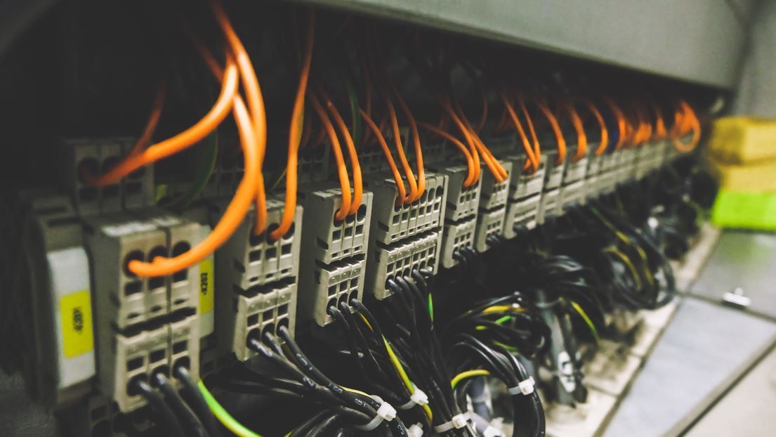 Panel eléctrico con cables naranja y negro conectados a terminales.