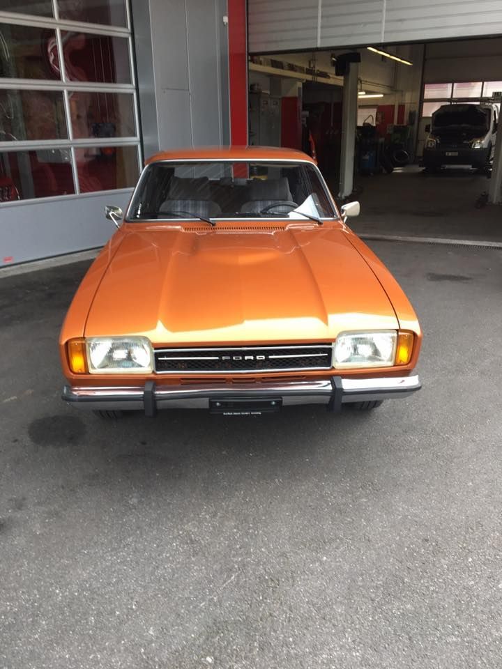 Draußen geparkter orangefarbener Oldtimer.