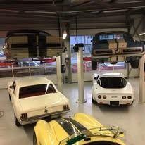 Weiße Oldtimer in einer Garage: Mustang, Corvette.