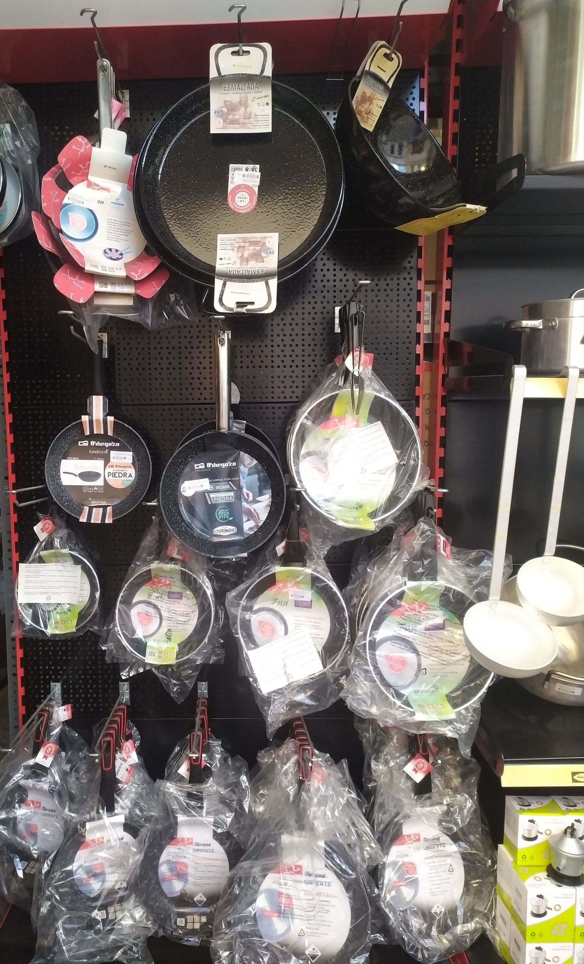 Una exhibición de ollas y sartenes colgadas en un estante en una tienda.