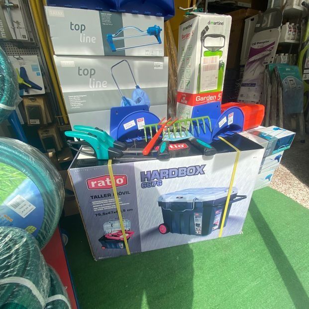 Una caja llena de una variedad de herramientas está sobre una alfombra verde en una tienda.