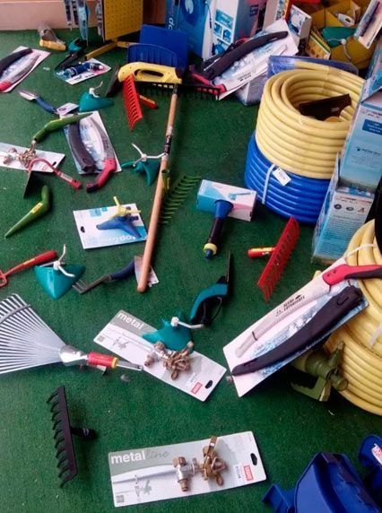 Un montón de herramientas de jardinería, incluido un rastrillo y una manguera.