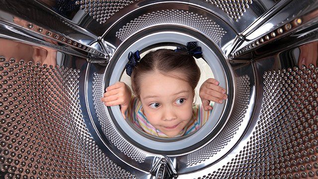 Jeune enfant regardant dans la machine à laver