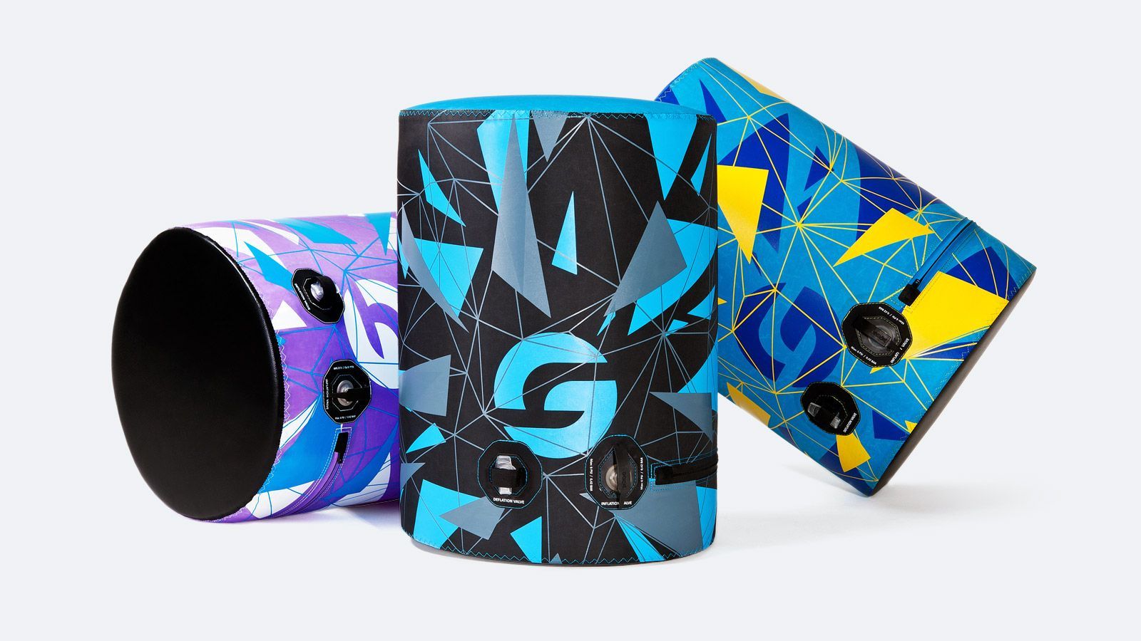 Three colorful cylindrical device cases with geometric blue, purple, black, and yellow designs