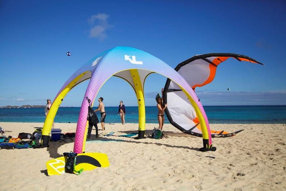 Colorful beach canopy tent on sandy shore with two people near calm blue ocean
