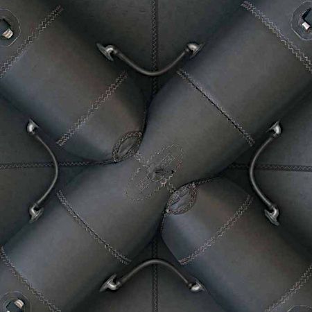 Abstract pattern of black quilted leather cushions with stitched seams and curved straps