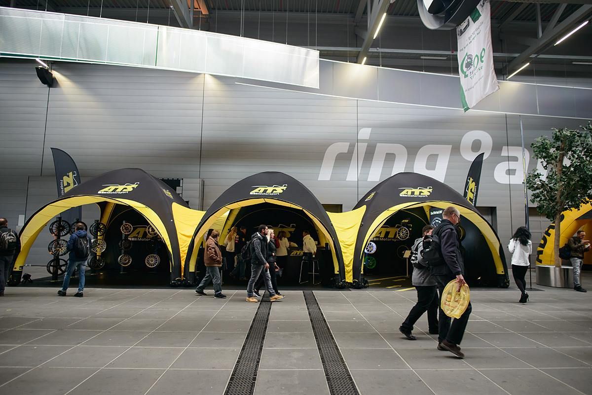 Indoor event with yellow-and-black tents, people walking, and large “ring” branding on the back wall