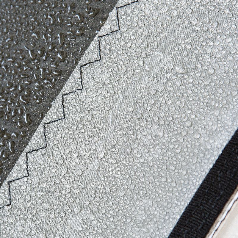 Close-up of wet, textured gray and black fabric with a zigzag seam and water droplets
