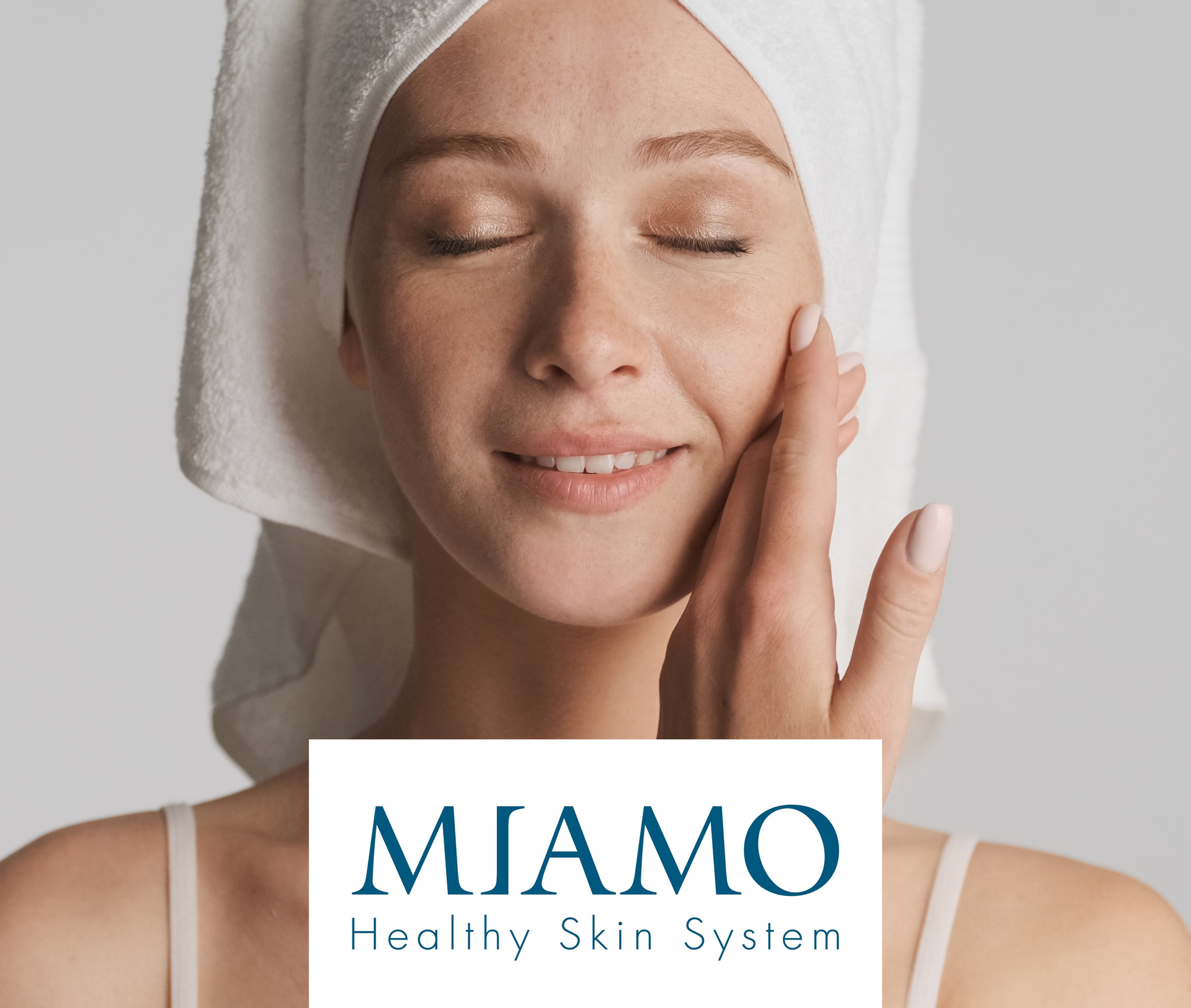 Donna con asciugamano sulla testa che tocca il viso, logo MIAMO Healthy Skin System.