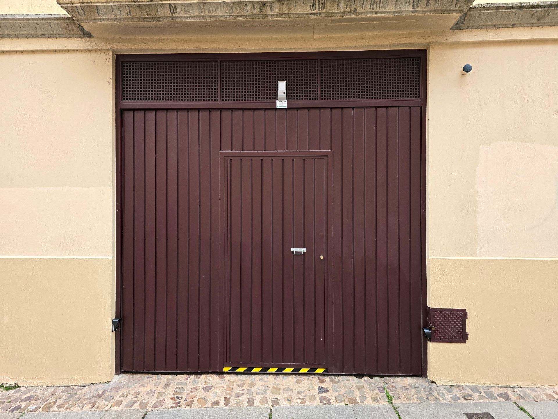 Casa blanca con una puerta de garaje verde y arbustos en flor a lo largo de la fachada delantera
