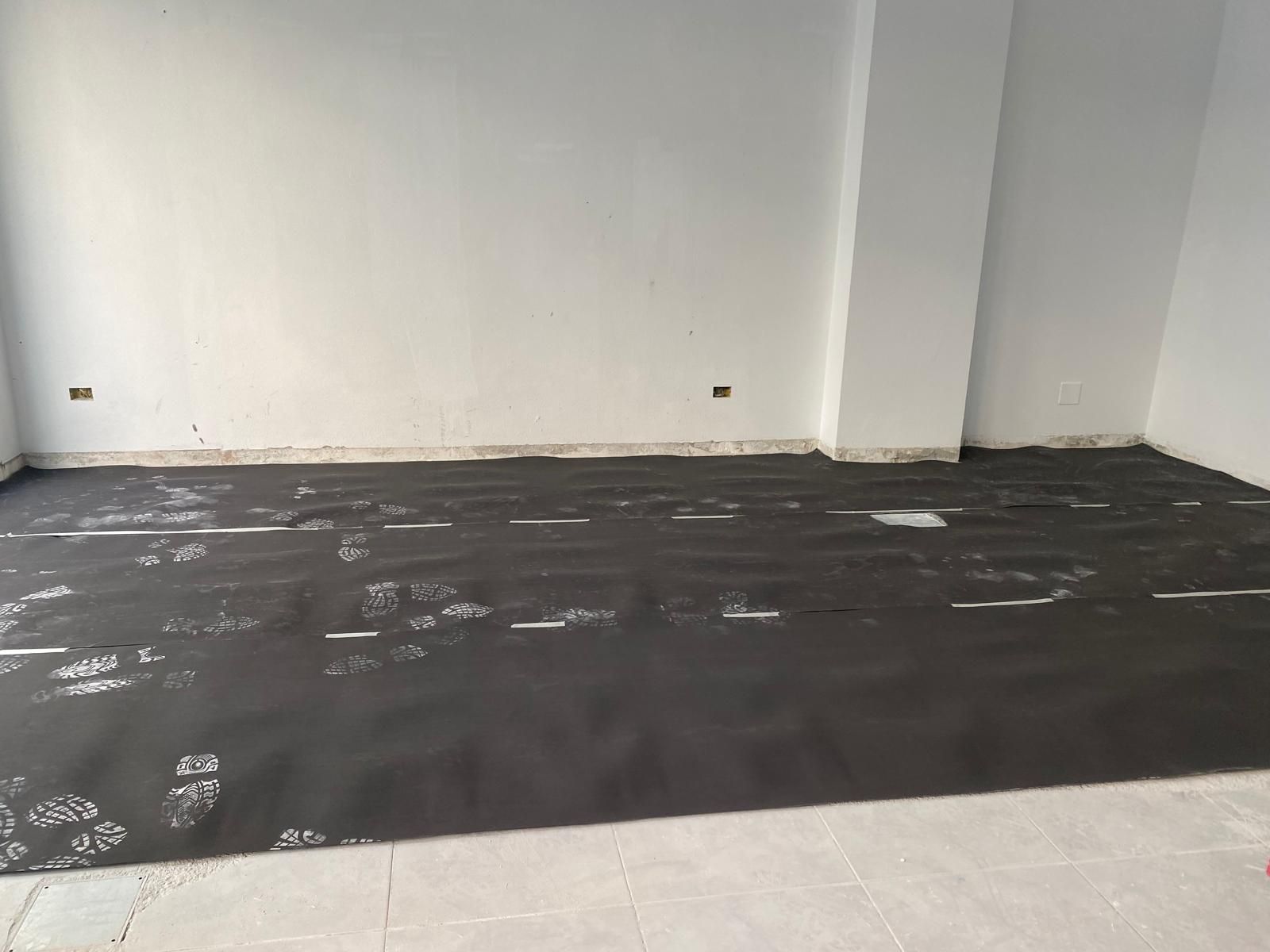 Habitación vacía con paredes blancas y suelo oscuro en construcción.
