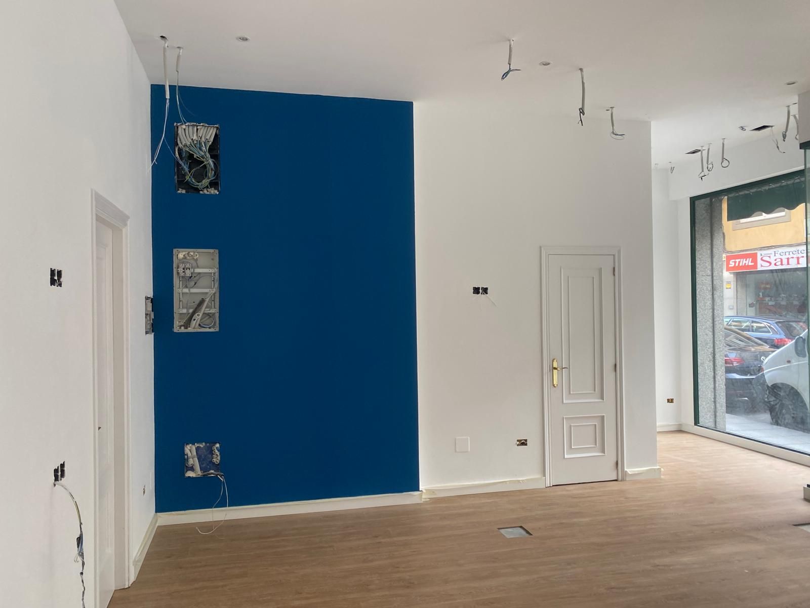 Habitación vacía con una pared decorativa azul, paredes y puertas blancas y una gran ventana frontal.