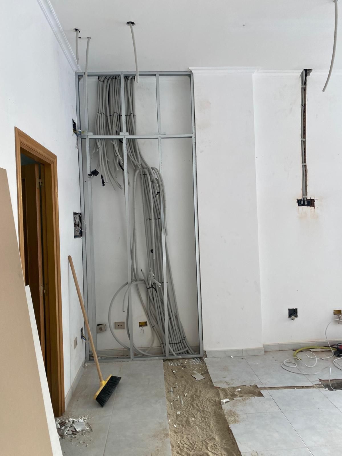 Habitación parcialmente reformada con cableado eléctrico a la vista en la pared y el techo.