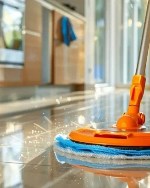 Fregona naranja limpiando un piso de baldosas brillantes en una cocina.