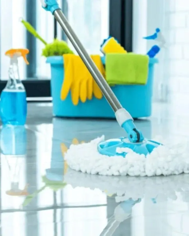 Trapeador para limpiar piso brillante, suministros de limpieza en un balde azul: guantes, esponja, botella de spray.