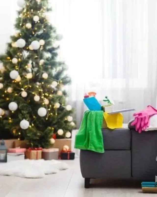 Árbol de Navidad con regalos junto a un sofá con productos de limpieza