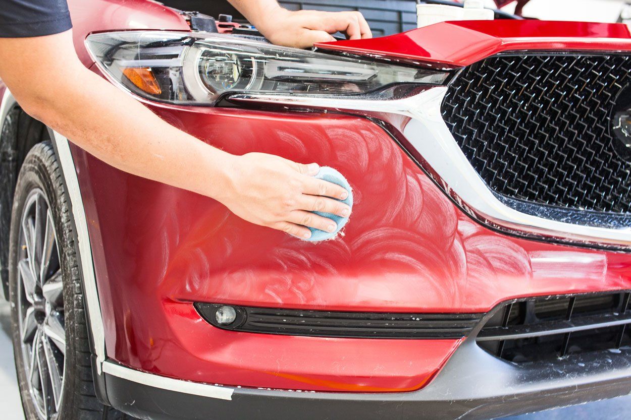 Professionnel nettoyant la carrosserie d'une voiture rouge