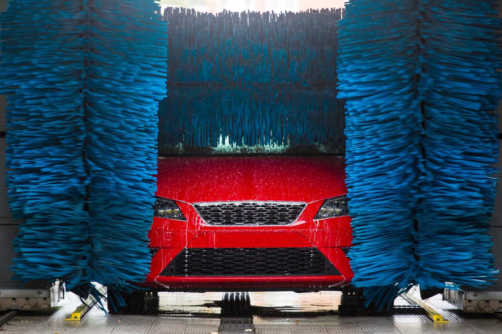 Voiture rouge passant dans les rouleaux d'une laverie