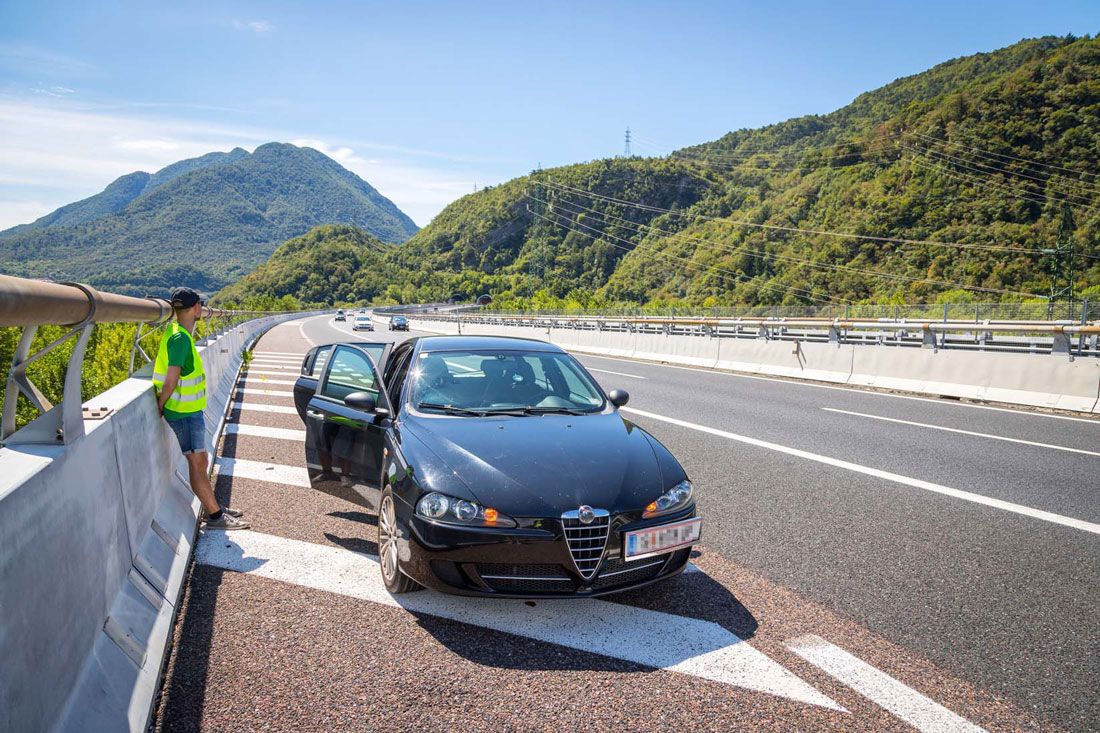 Voiture en panne sur un pont avec le conducteur qui a un gilet jaune