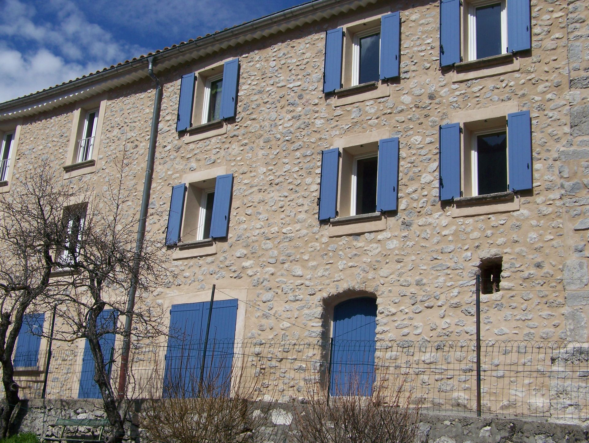 Maison en pierre aux volets bleus