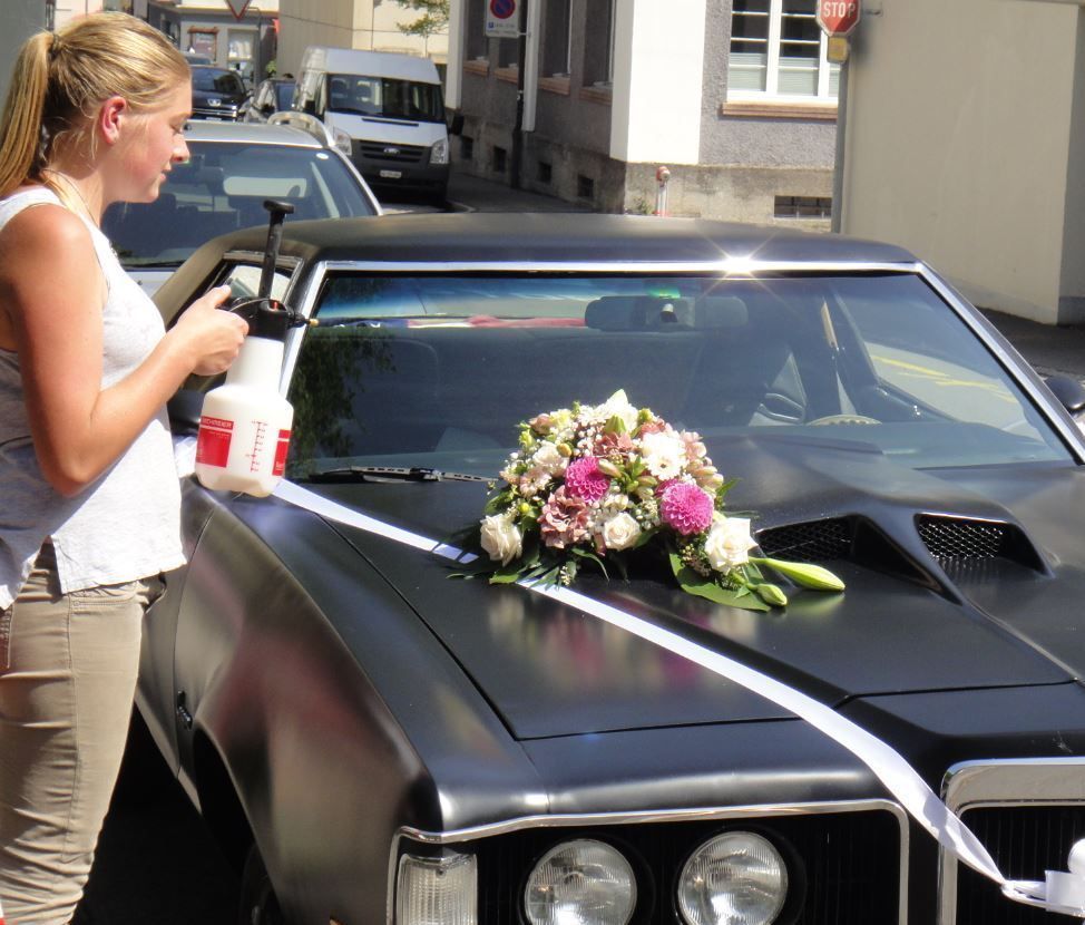 Frau vor Auto mit Blumendekoration