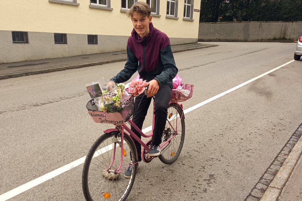 Junge liefert auf dem Fahrrad Blumen aus