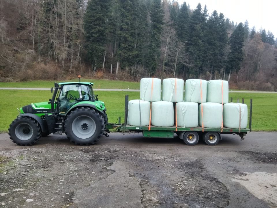 Vogler Lohnunternehmung – Traktor mit Anhänger mit verpackten Strohballen