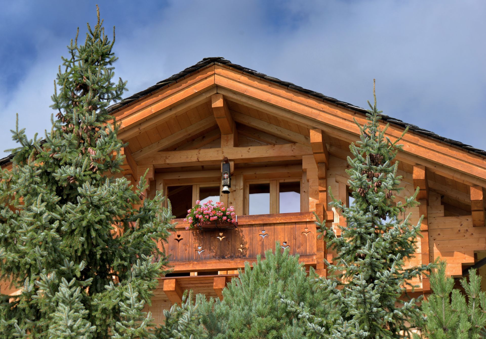 Verschneites Holzchalet eingebettet in eine verschneite Berglandschaft; drinnen Licht an, gemütlich und einladend.