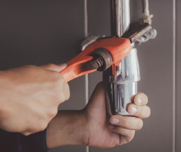 Holzspielzeughaus mit Werkzeugen: Schraubenschlüssel, Säge, Schlüssel; vor Holzhintergrund.