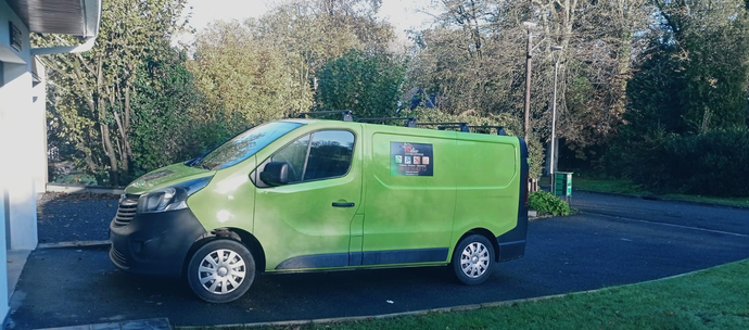 Camionnette verte garée dans une allée devant des arbres.