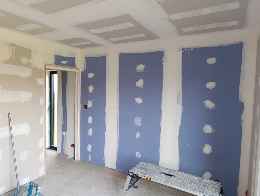 Intérieur de la pièce avec échelle et travaux de cloisons sèches en cours; murs verts.