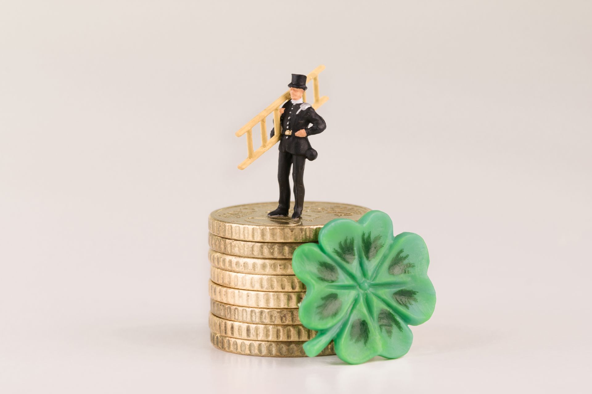 Figurine de ramoneur sur pièces d'or à côté d'un trèfle à quatre feuilles.