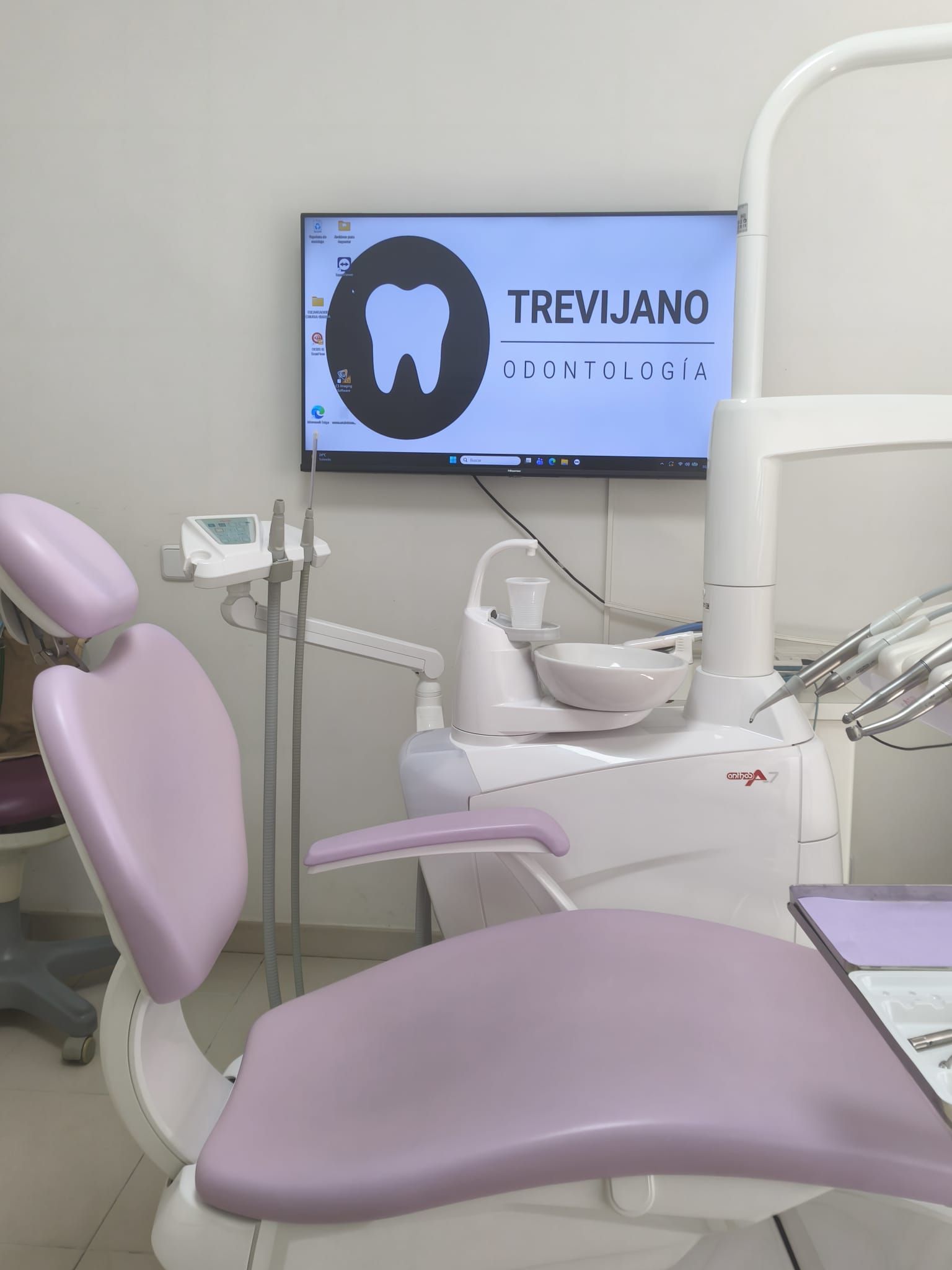 Clínica dental con sillones de color lavanda, instrumental de tratamiento y una pantalla que muestra el logotipo
