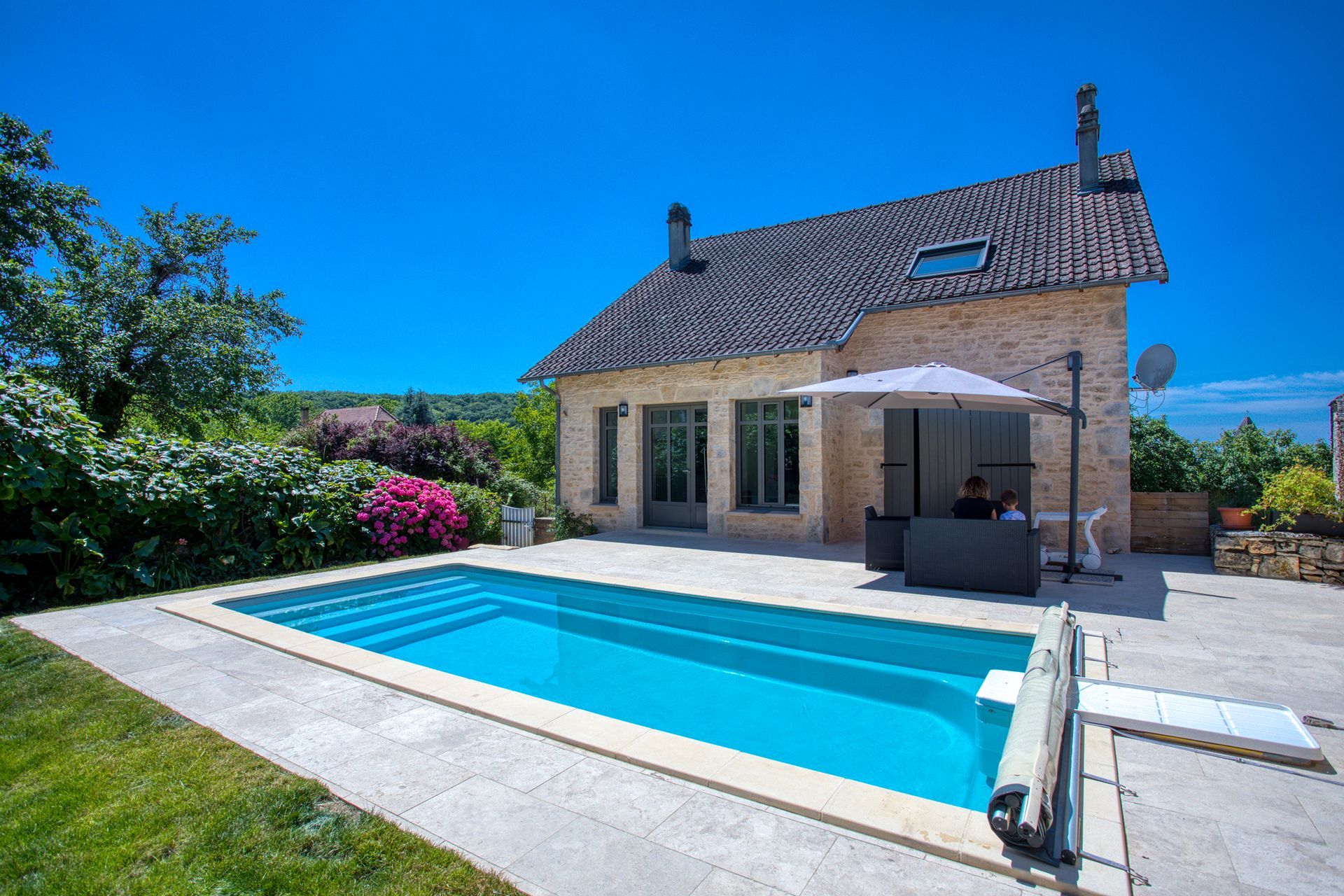 Piscine devant une maison avec un beau jardin