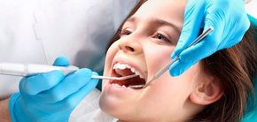 A una niña le están examinando los dientes un dentista.