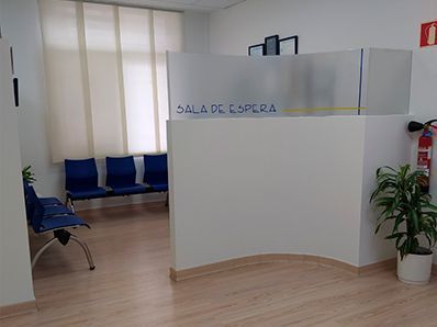Una sala de espera con sillas azules y un extintor de incendios.
