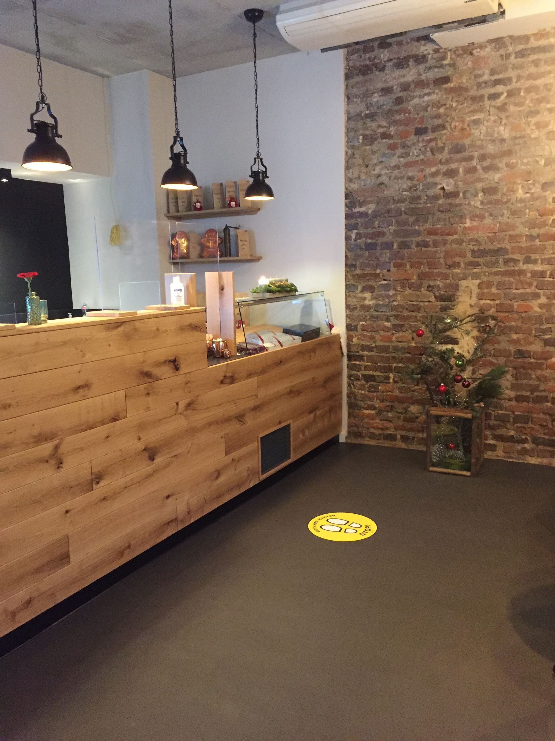 Modernes Café mit Holztheke, Backsteinwand und kleinem Weihnachtsbaum.