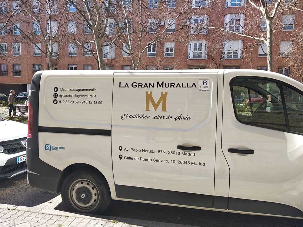 Una camioneta blanca está estacionada frente a un edificio de ladrillo.