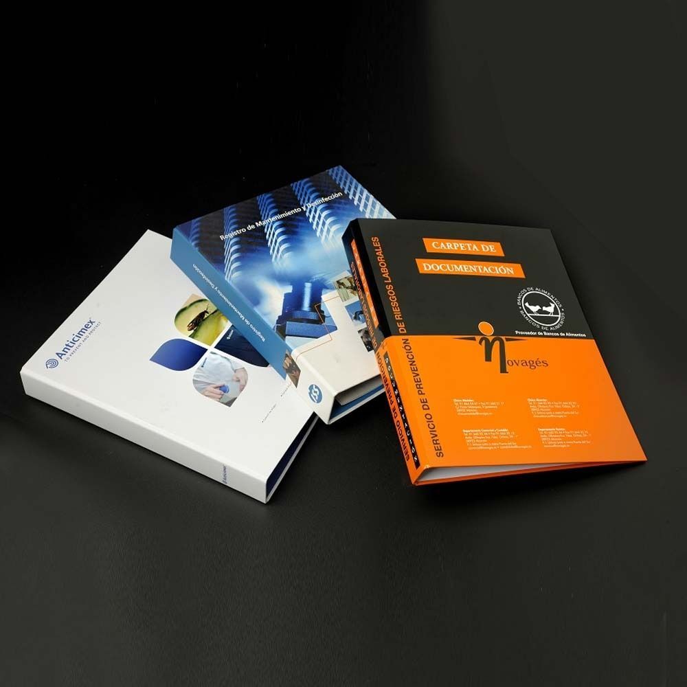 Tres carpetas están apiladas una encima de otra sobre una superficie negra