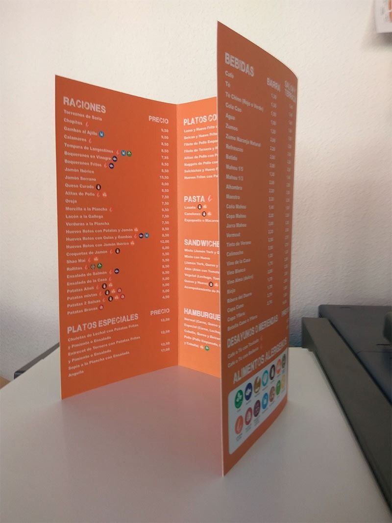 Un menú naranja está sobre una mesa blanca.