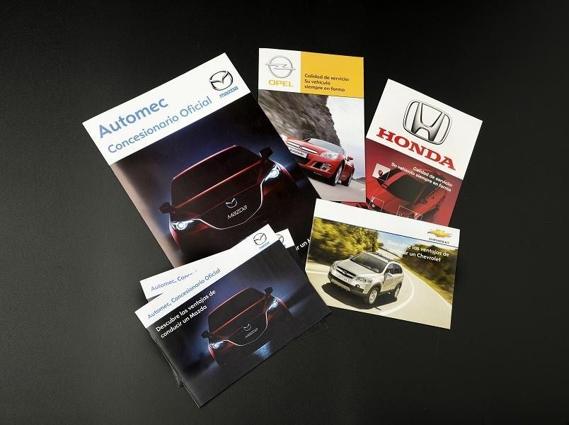 Hay folletos de Mazda, Honda y Opel sobre una mesa.