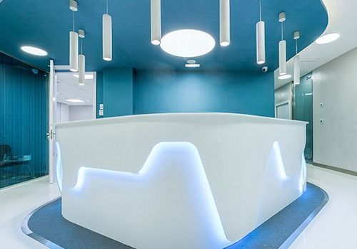 Una moderna área de recepción con un mostrador blanco y paredes azules.