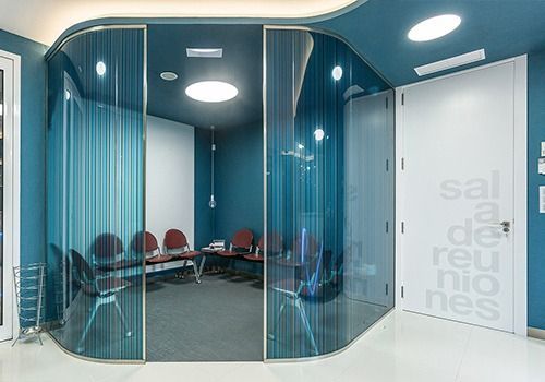 Una sala de espera con paredes azules y una pared de cristal.